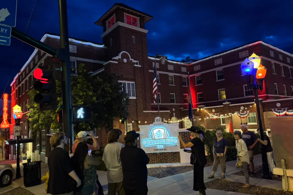 Tour group gathered at the Hassayampa Inn sign in downtown Prescott at dusk