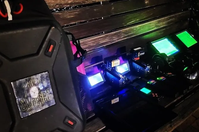 Glowing paranormal investigation equipment arrayed on a wooden bench in the dark