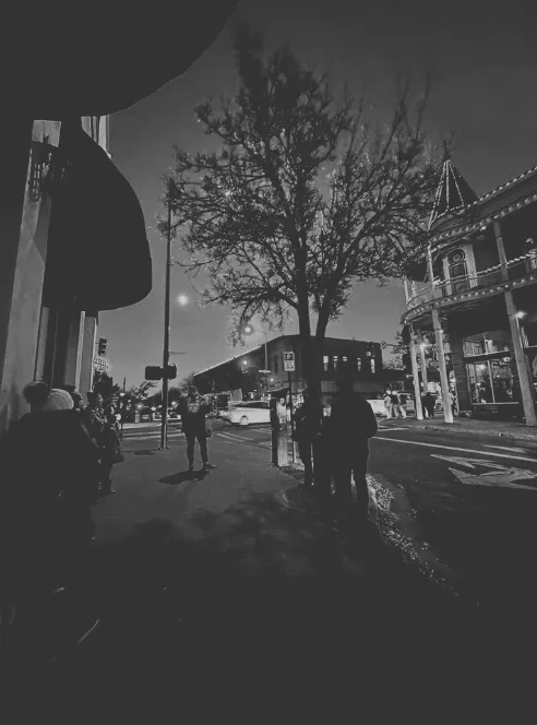 Black and white night street scene with a turreted building and small group in downtown Flagstaff