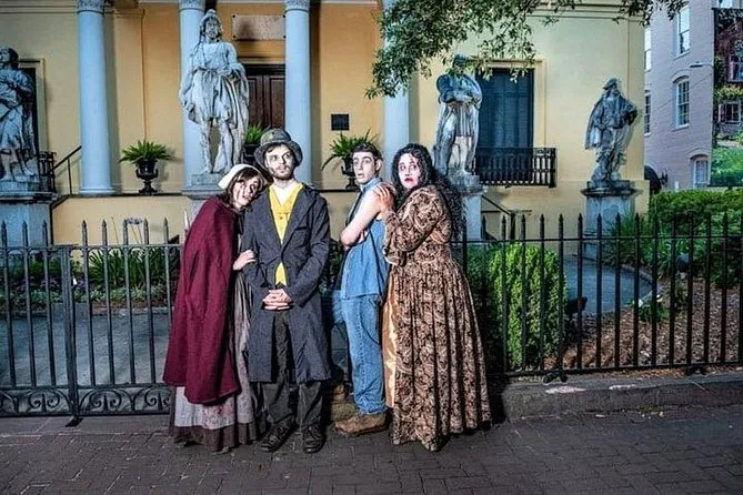 Costumed guides in period dress posing at night before a statue-lined mansion