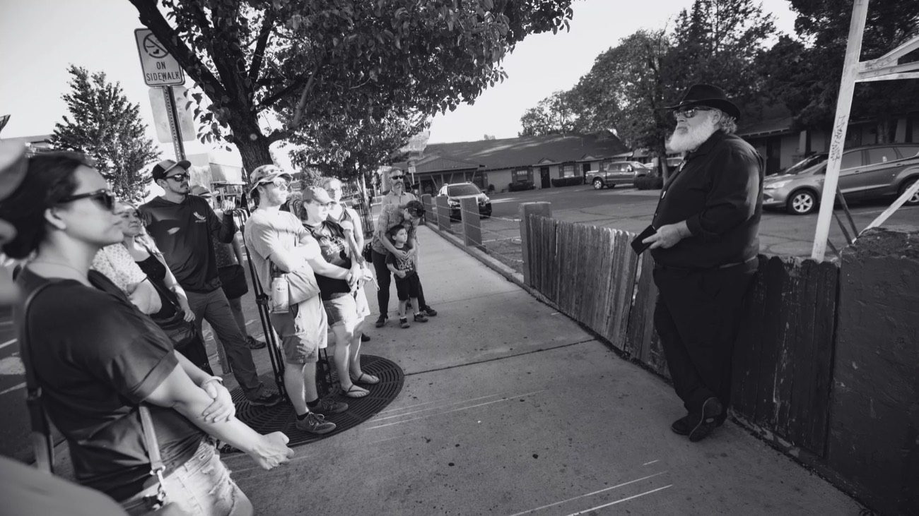 Black and white walking tour group listening to a guide on a sidewalk