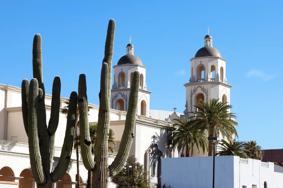 White twin-domed Spanish colonial cathedral behind tall saguaro cactus in Tucson