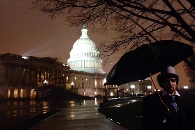 Costumed guide with an umbrella near the lit US Capitol dome at night