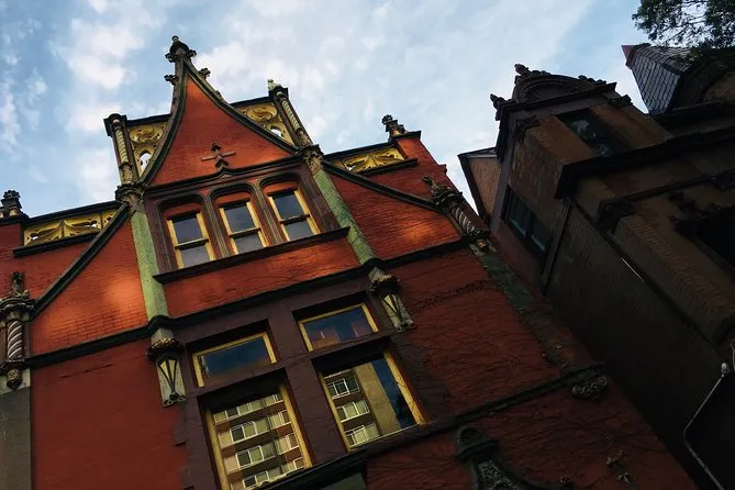 Ornate red-brick Victorian building at dusk with gilded gables