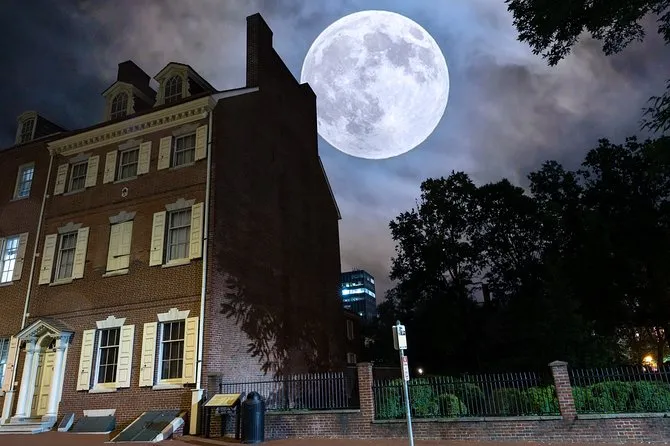 Full moon rising over a brick colonial rowhouse at night