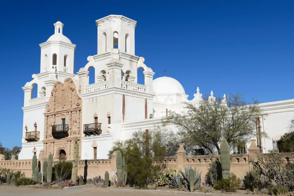 White Spanish mission church with twin towers and domes under a clear sky in Tucson
