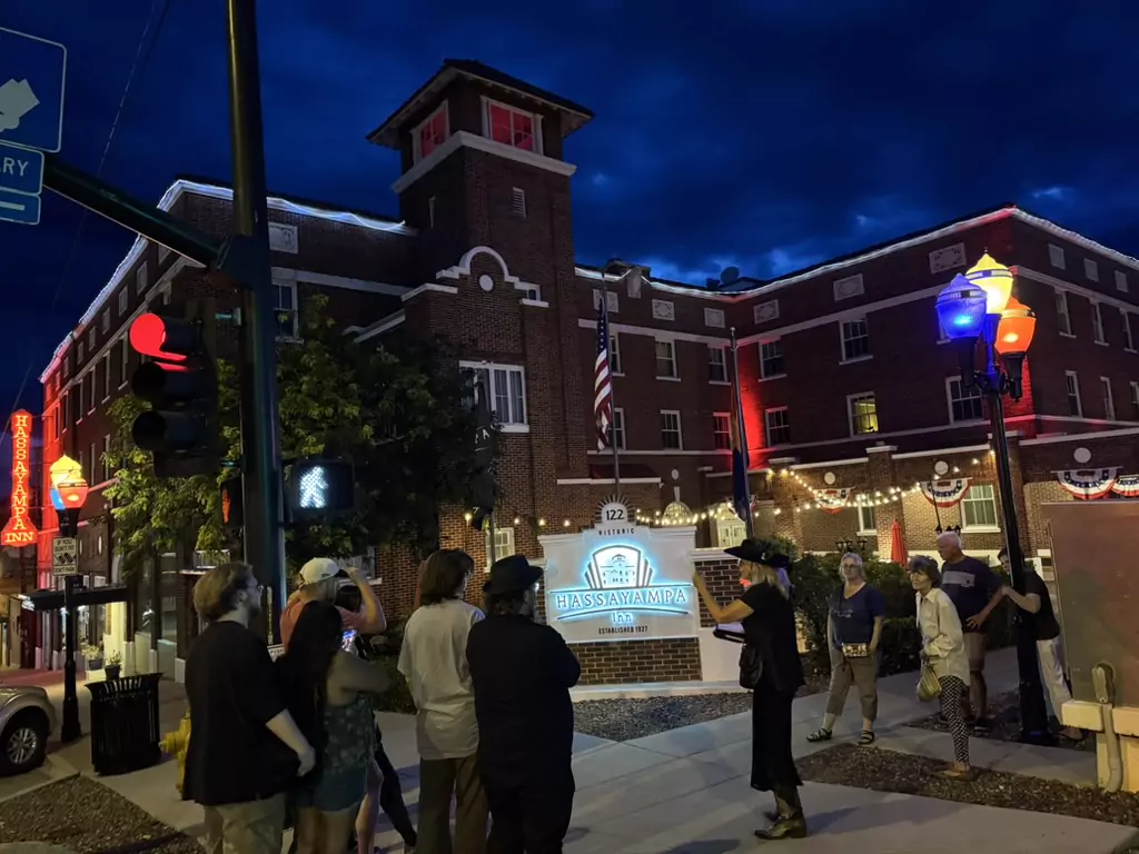 Night ghost tour group gathered outside the illuminated brick Hassayampa Inn in Prescott