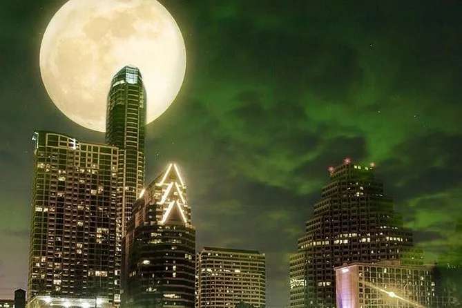 City skyline at night under a large moon and green-tinted sky