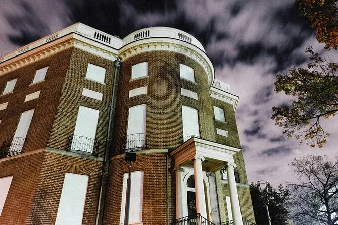 Historic brick building with a rounded corner tower under a cloud-streaked night sky