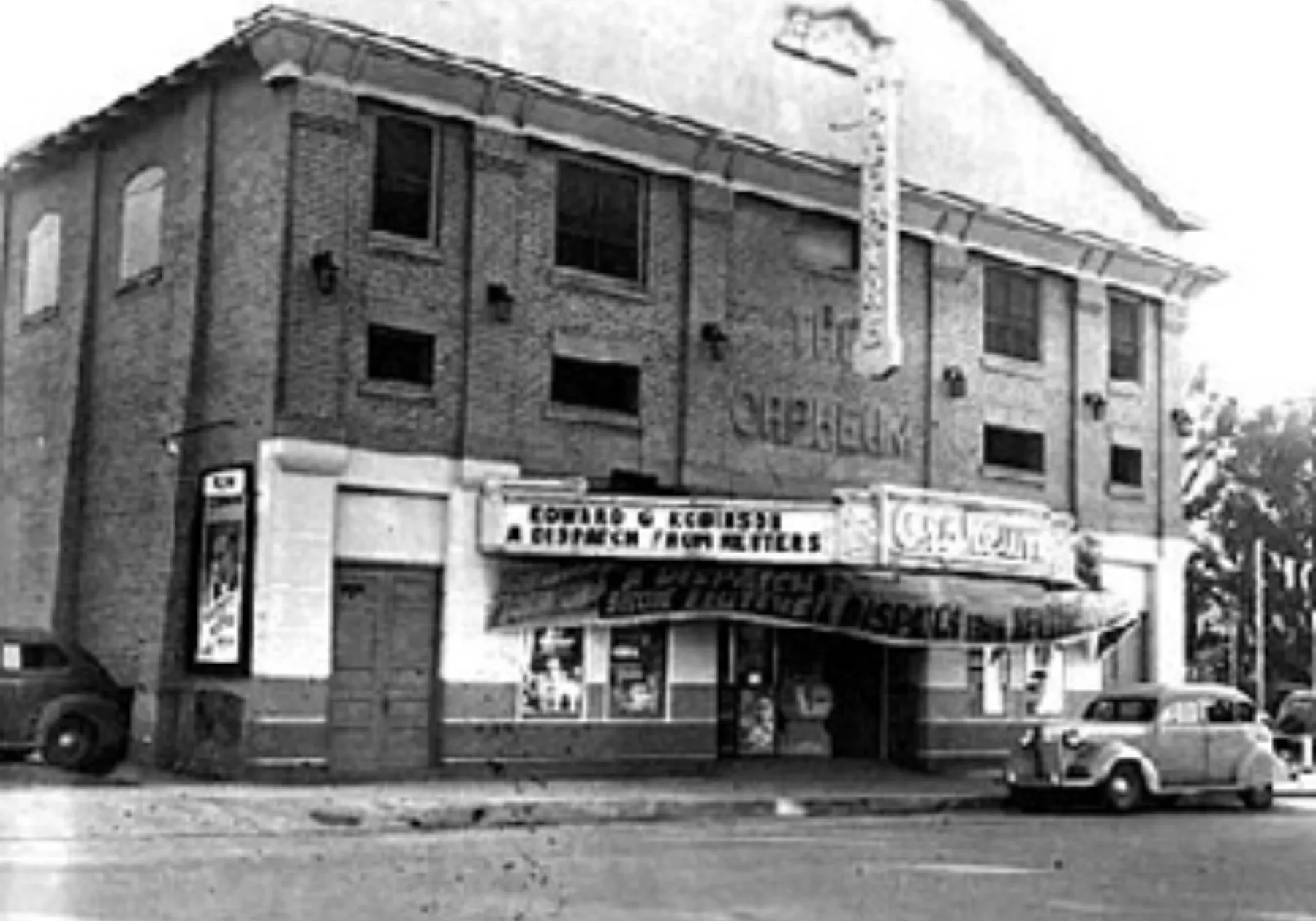 Historic Orpheum theater with a lit marquee and 1940s cars parked out front