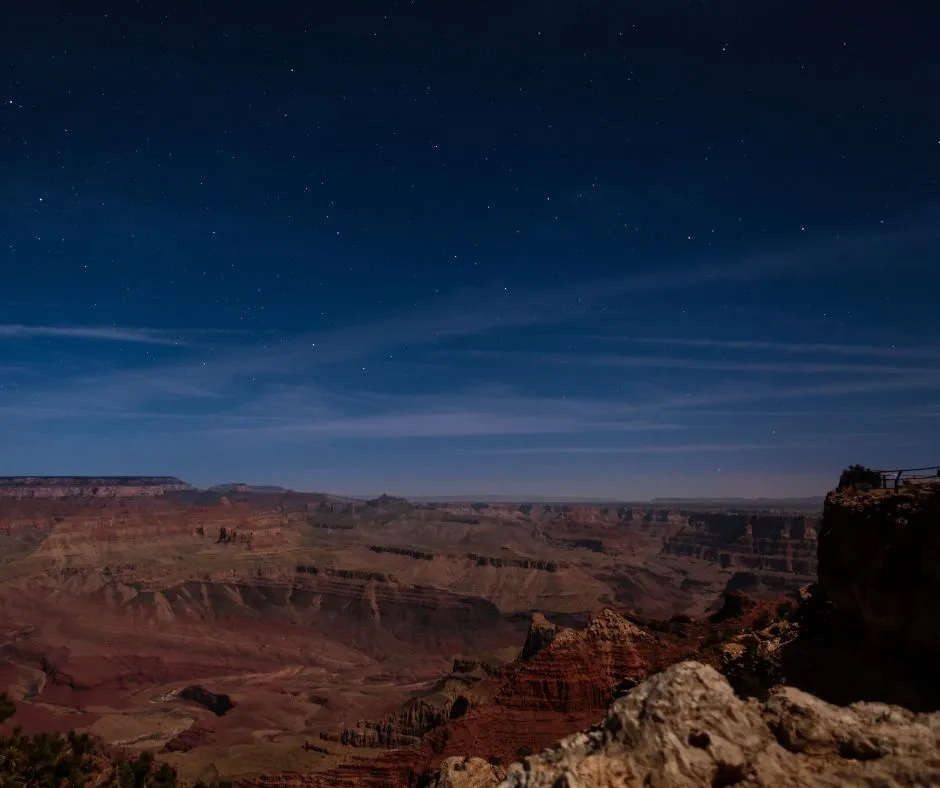 Layered red-rock canyon cliffs under a starry twilight sky