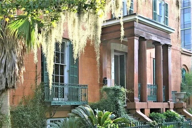 Stucco mansion with columns and iron balcony draped in Spanish moss