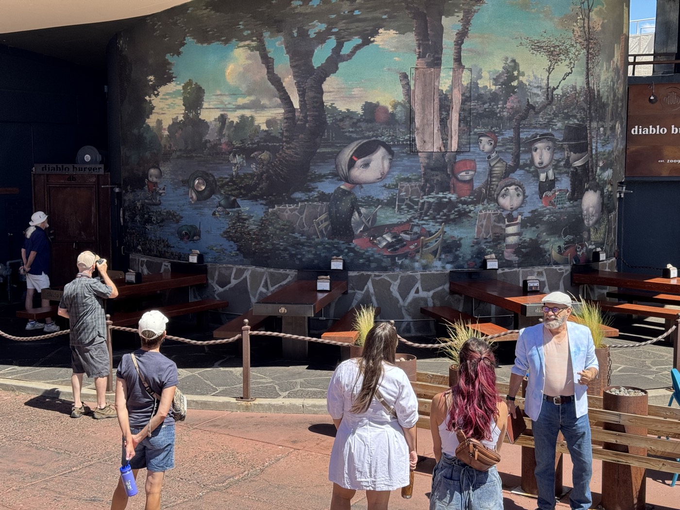 The patio at Diablo Burger doubles as a gallery, where a dreamlike storybook scene unfolds behind the picnic tables.