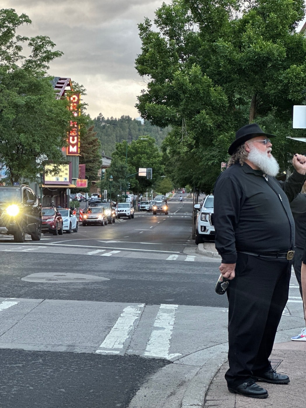 A black-clad guide pauses mid-story as the Orpheum Theater's neon warms the dusk down West Aspen Avenue.