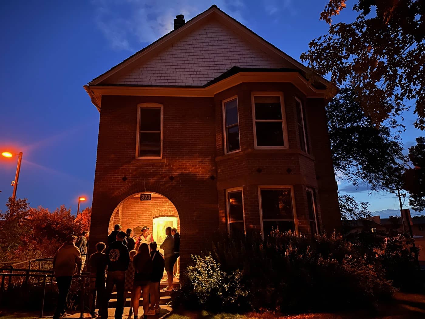 The lamp-lit archway of the Milligan House swallows the tour one story at a time, the moon riding above the gable.