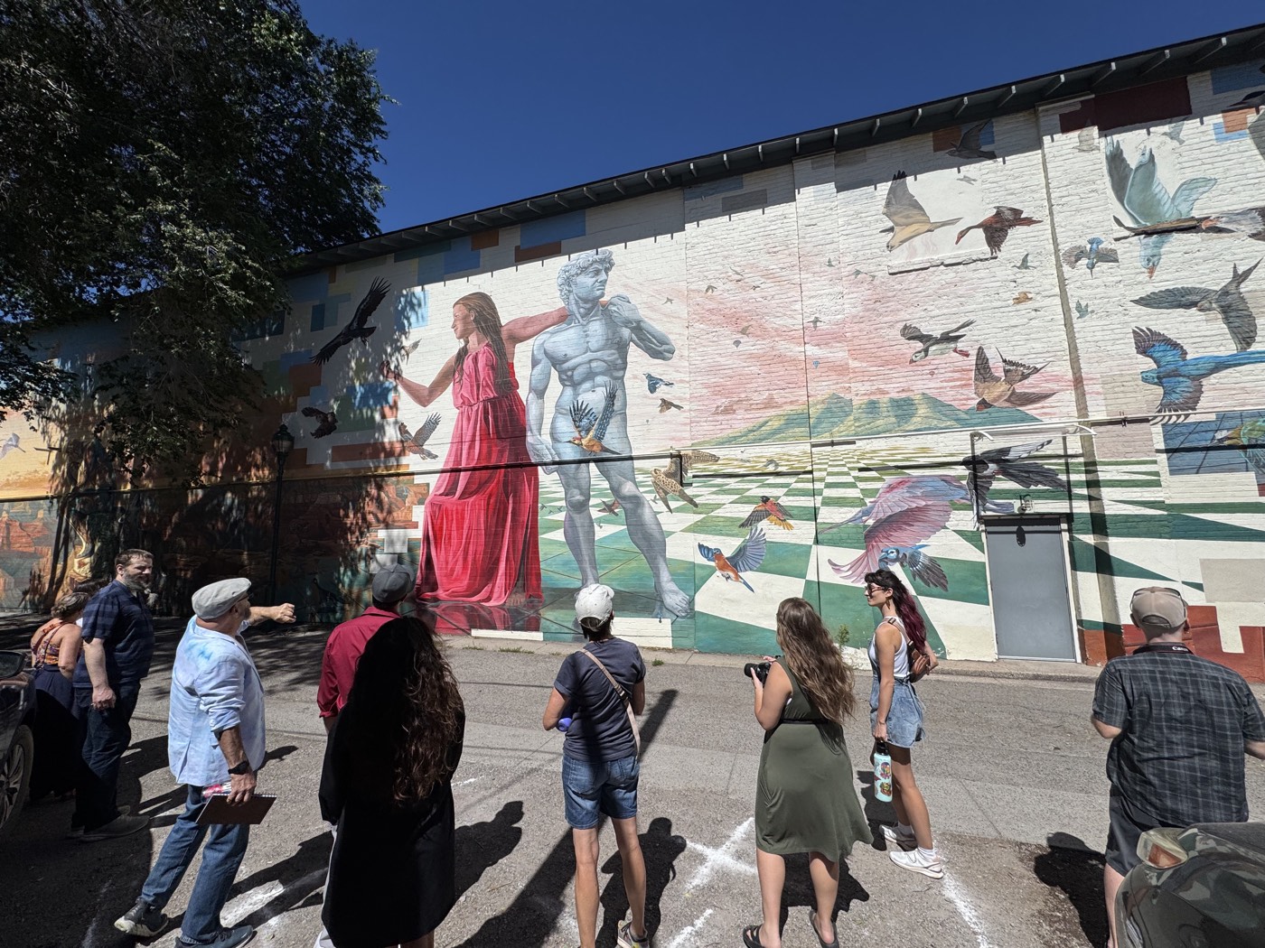 The full sweep of the peace mural comes into view as walkers trace its wildflowers down the alley.