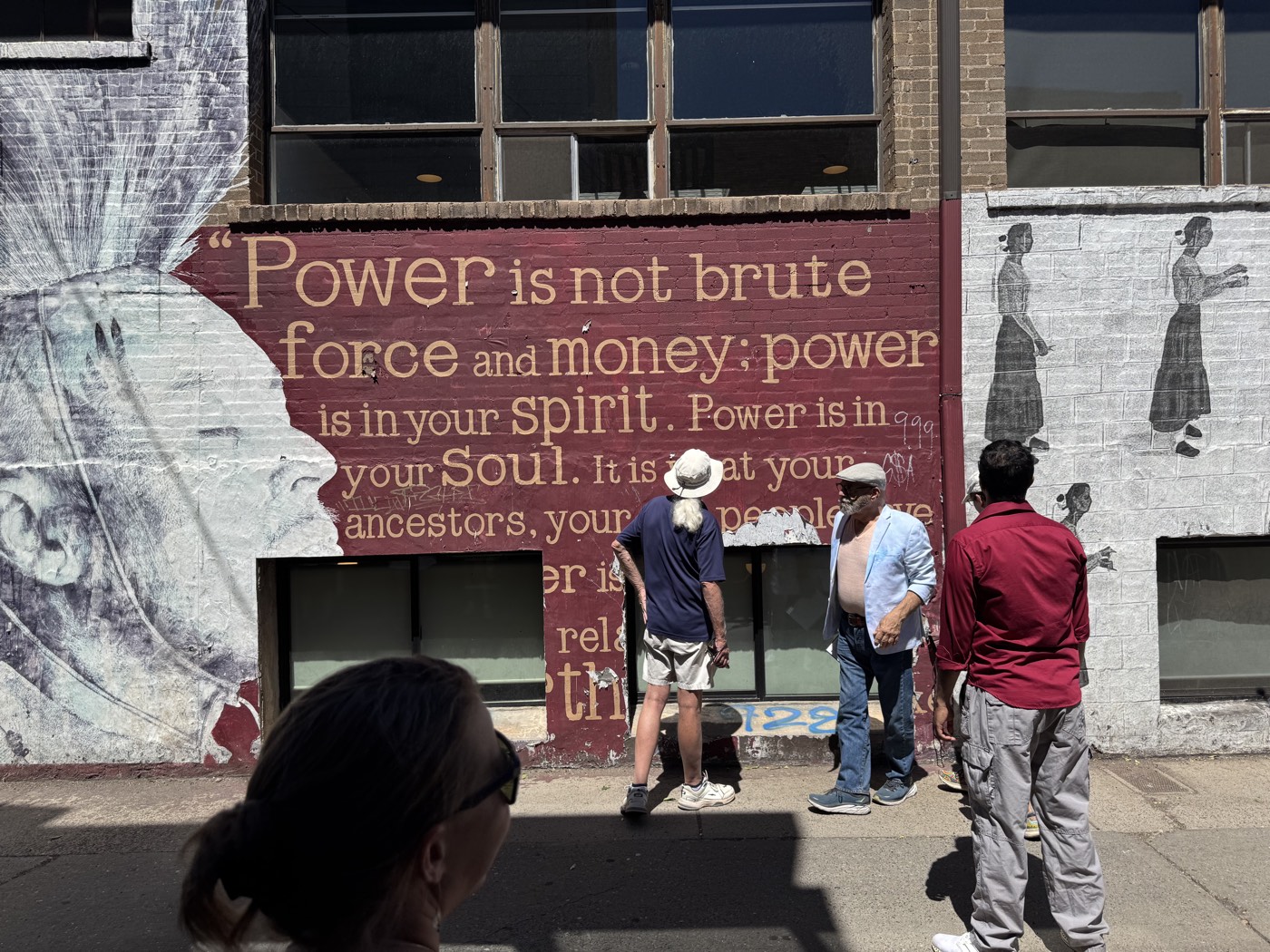 Walkers stop to read a rooftop-high reminder that power lives in spirit and soul, not brute force and money.