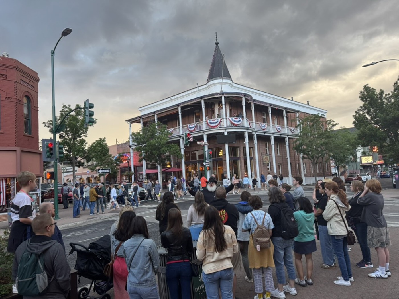 Walking tour group gathered before a historic turreted building at dusk in Flagstaff