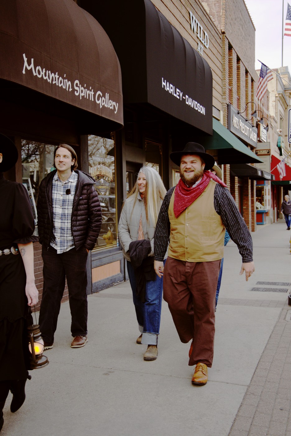 A Freaky Foot Tours group walks along Montezuma Street past Mountain Spirit Gallery on Prescott's Whiskey Row, where frontier saloons and modern shops share the same historic storefronts.