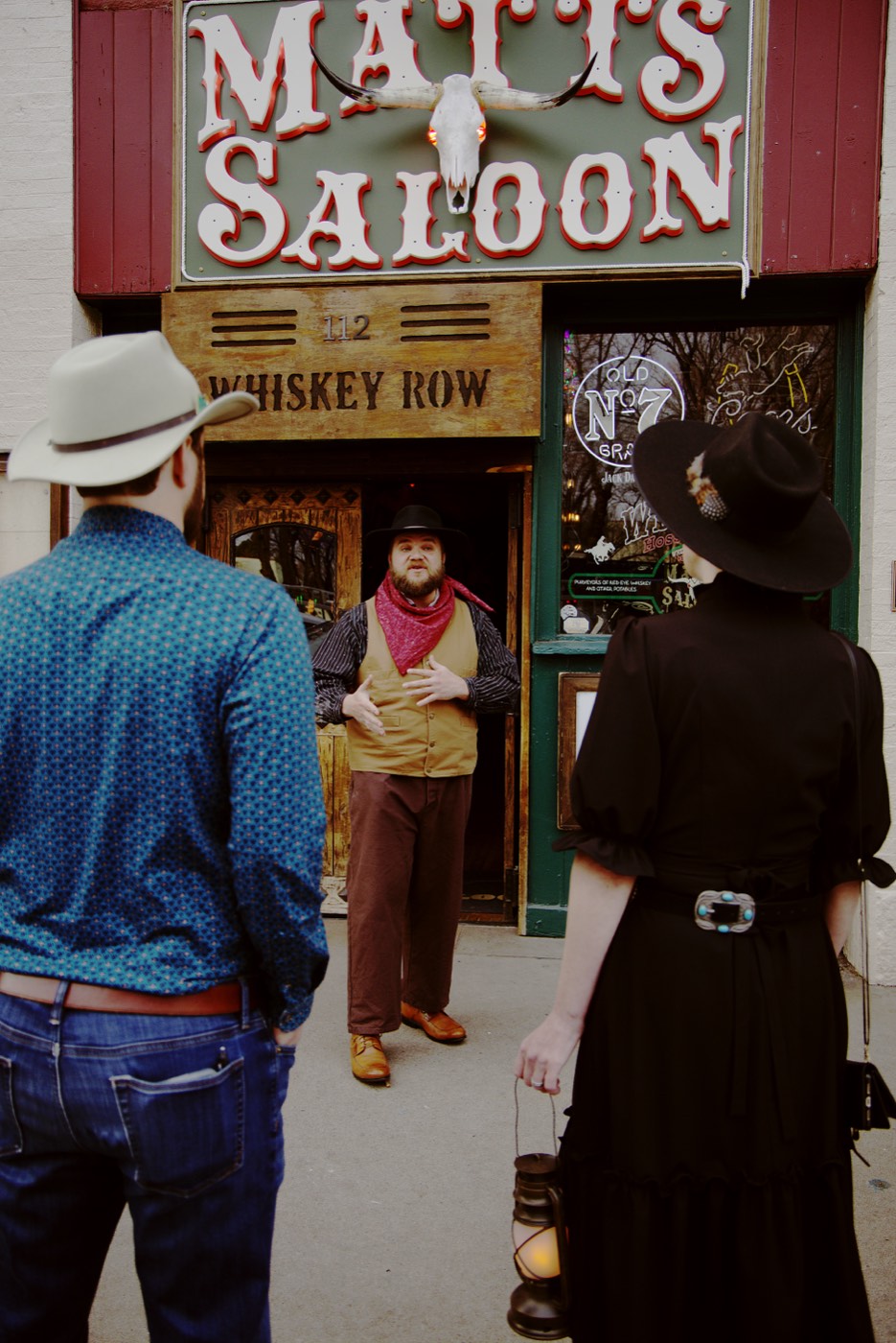 A costumed guide speaks at Matt's Saloon on Whiskey Row while fellow guides listen, sharing the story of the ghost girl who has been reported pulling patrons' arms inside.