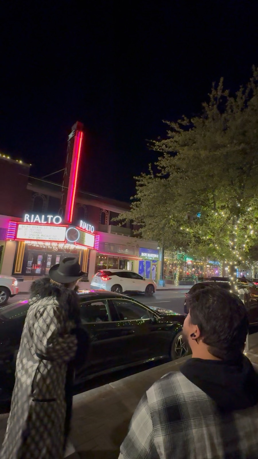 A tour group under the Rialto Theatre neon at night