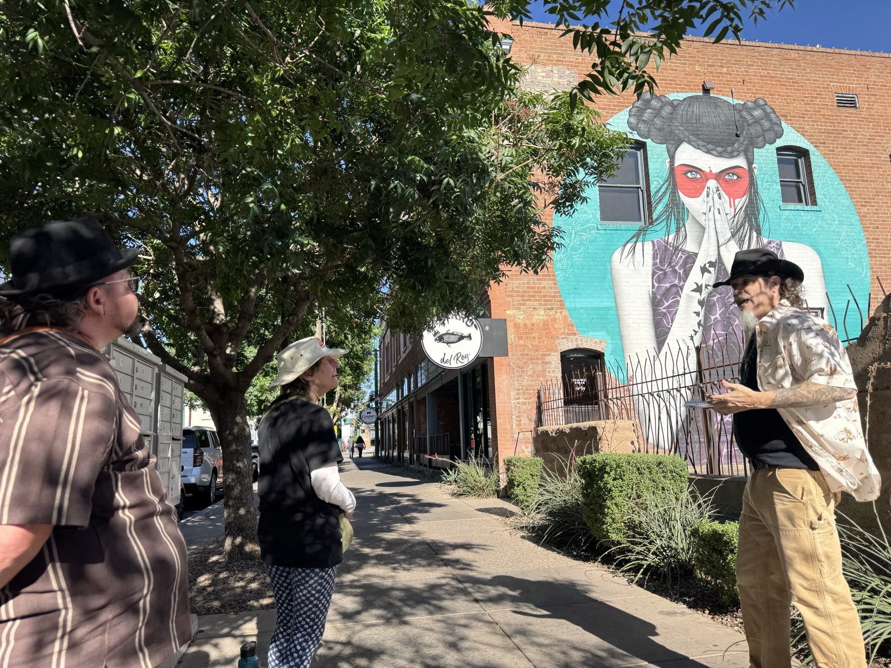 A Freaky Foot Tours guide beneath Fin DAC's Vergiss mural on Broadway in downtown Tucson